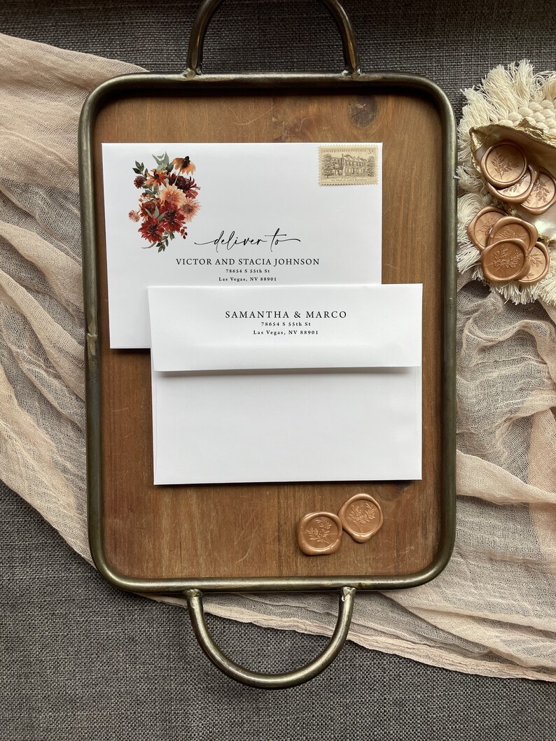 May include: A white envelope with a floral design and the text "deliver to" followed by an address. The envelope is on a wooden tray with two wax seals.