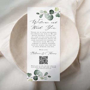 May include: A wedding thank you card with a green watercolor eucalyptus design. The card says "Welcome and Thank You" and includes a QR code. The text reads: "Thank you so much for sharing our special day with us. We are beyond thankful to have you as a part of our lives and our wedding celebration. Enjoy the food and have fun tonight on the dance floor. We look forward to making memories with you during this first day of being husband and wife. With love, Melanie & Thomas. We'd love to see the day through your eyes. Scan the code to share your photos with us!"