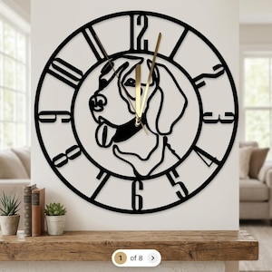 May include: A circular wall clock featuring a black metal frame with large cut-out numerals. The center displays a stylized line art silhouette of a dog head with its tongue out. Two thin gold-colored hands indicate the time on the open face.