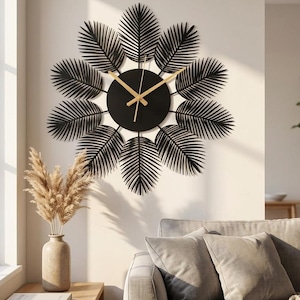 May include: A circular wall clock featuring a black center dial with gold-colored hands. The clock is surrounded by twelve black metal palm leaf-shaped accents arranged in a radial pattern, creating a sunburst effect against the wall.