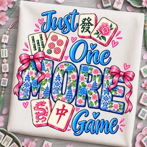 Puede incluir: Una superficie de tela blanca con un estampado gráfico que incluye el texto "Just One MORE Game" en azul. El diseño presenta ilustraciones de fichas de mahjong, lazos rosas y patrones florales en azul y rosa, con pequeños corazones rosas.