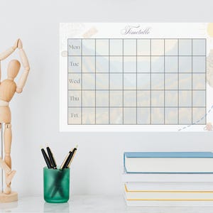 May include: A rectangular wall planner featuring the word Timetable at the top, with a grid layout labeled Mon, Tue, Wed, Thu, and Fri. The background of the grid displays a faint, muted landscape image of mountains and trees in soft tones.
