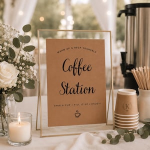 May include: A rectangular sign in a thin gold metal frame with a tan background and black text that reads: WARM UP & HELP YOURSELF, Coffee Station, TAKE A CUP • FILL IT UP • ENJOY! and a small icon of a coffee cup centered at the bottom.