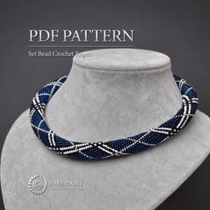 May include: A PDF pattern for a bead crochet rope necklace featuring a dark blue, white, and black geometric diamond pattern. The text PDF PATTERN and Set Bead Crochet Ropes is visible at the top, with the Emerant logo at the bottom left.