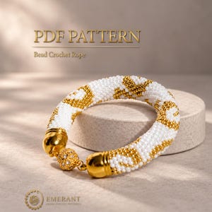 May include: A bead crochet rope bracelet featuring a repeating pattern of white and metallic gold beads. The bracelet includes polished gold-tone end caps and a spherical clasp. The text PDF PATTERN Bead Crochet Rope is visible.