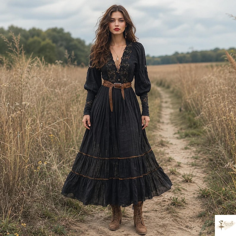 May include: A long-sleeved black maxi dress featuring a deep V-neckline with intricate lace detailing, a button-down front, and a tiered skirt. The dress is cinched at the waist with a brown leather belt and paired with brown lace-up ankle boots.