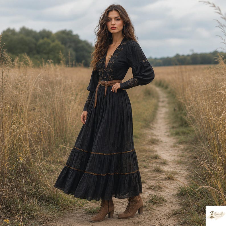 May include: A long-sleeved black maxi dress featuring a V-neckline, intricate lace detailing on the bodice and sleeves, a tiered skirt, and a brown leather belt with a buckle. The dress is paired with brown ankle boots.