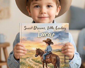 May include: A square hardcover book titled Sweet Dreams, Little Cowboy with the name Lucas printed on the front cover. The cover illustration features a young child in a cowboy hat riding a brown horse on a dirt path at sunset.