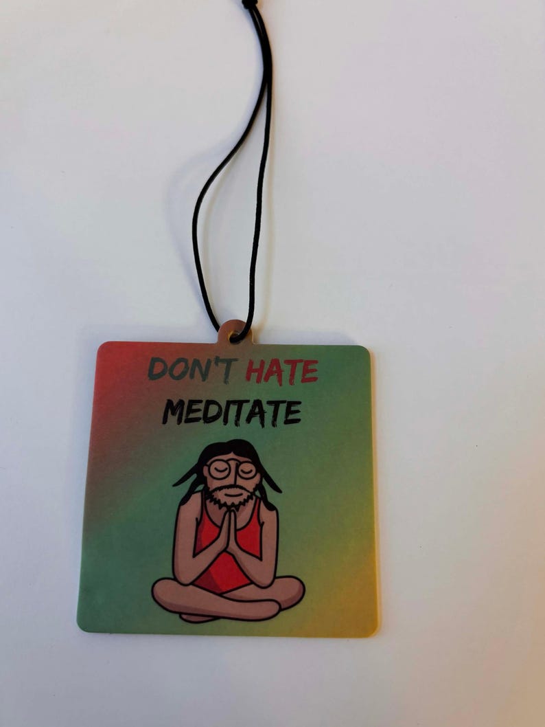 Może przedstawiać: Kwadratowy odświeżacz powietrza z napisem "DON'T HATE MEDITATE" nad kresk&oacute;wkową ilustracją medytującej osoby. Odświeżacz powietrza ma gradientowe tło w kolorach czerwonym, zielonym i ż&oacute;łtym. Do zawieszenia przymocowany jest czarny sznurek.