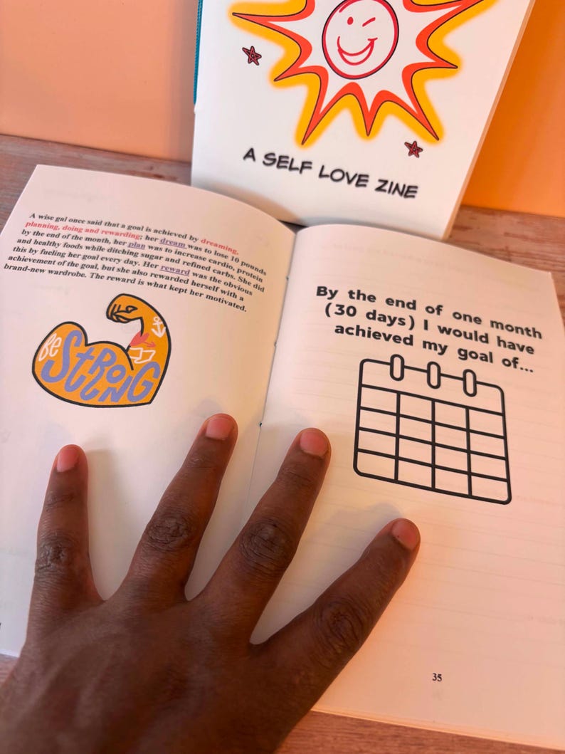May include: A self-love zine with the text "A SELF LOVE ZINE" on the cover. The open pages show text and a calendar graphic. The text includes the phrase "By the end of one month (30 days) I would have achieved my goal of..."