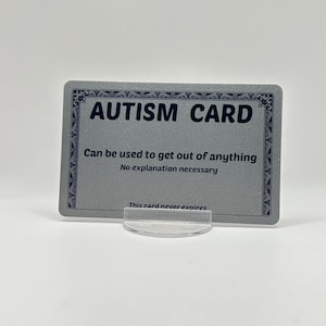 May include: A rectangular silver card with a decorative black border. The text reads: AUTISM CARD, Can be used to get out of anything, No explanation necessary, This card never expires. The card is held upright by a small, clear plastic stand.