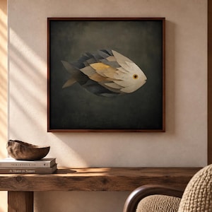 Può includere: Un'opera d'arte da parete quadrata incorniciata raffigurante un pesce stilizzato composto da strati sovrapposti a forma di foglia in tonalità crema, oro e grigio scuro, su uno sfondo scuro e strutturato con un occhio giallo ben visibile.