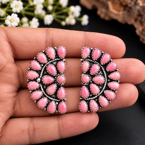 May include: A pair of semi-circular earrings featuring multiple teardrop-shaped pink stones set in oxidized silver. Each earring is arranged in a fan-like pattern with a twisted silver rope border surrounding the pink cabochon stones.