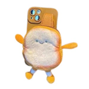 May include: A mustard yellow smartphone case featuring an attached plush, fuzzy bread-shaped pouch. The pouch has a white center, brown crust edges, small outstretched arms, and two dangling legs with yellow feet, plus a simple embroidered face.