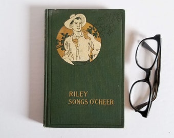 May include: A green hardcover book with a gold title, "Riley Songs O'Cheer". The cover features an illustration of a man in a straw hat and a white shirt standing in a field.