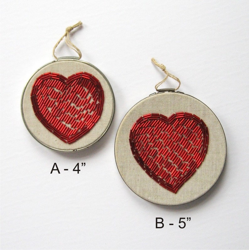 May include: Two embroidered heart-shaped wall hangings with red beading. The smaller one is 4 inches in diameter and the larger one is 5 inches in diameter.
