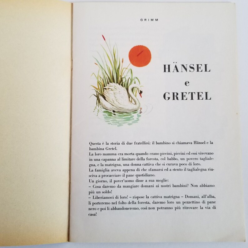May include: An illustrated book cover featuring a white swan swimming in a pond with green reeds and a red sun in the background. The title of the book is "HANSEL e GRETEL" in large, bold letters.