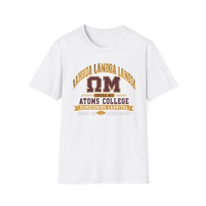 May include: White t-shirt featuring a maroon and gold design. The design includes the words "Lambda Lambda Lambda" arched across the top, with "Omega Mu" and "Atoms College" below. A banner reads "Homecoming Carnival".