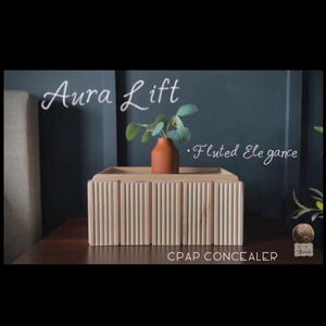 May include: A rectangular light-colored wooden box with a vertical fluted texture on the sides. A small terracotta-colored vase with green leaves sits on top. The text Aura Lift, Fluted Elegance, and CPAP CONCEALER are visible on the image.