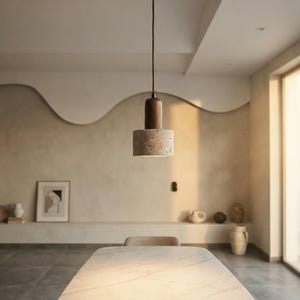 May include: A pendant light fixture featuring a cylindrical dark wood top section connected to a textured, light gray stone base. The light hangs from a thin cord attached to a matching dark wood circular ceiling canopy, casting a downward glow.