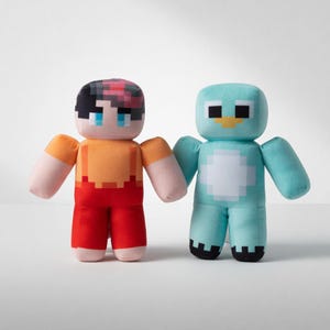 Puede incluir: Dos peluches: uno que se asemeja a una figura humana con ropa naranja y roja, y el otro una criatura azul parecida a un pingüino. La figura humana tiene cabello y rasgos faciales pixelados. El pingüino tiene vientre blanco y pies negros. Ambos juguetes tienen los brazos extendidos.
