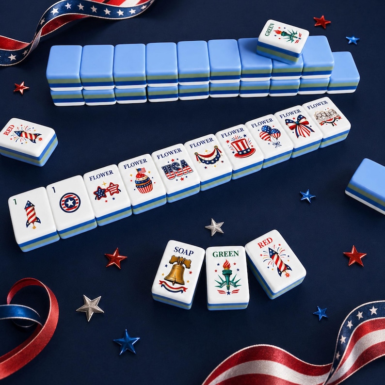 Puede incluir: Un juego de fichas de Mahjong azules y blancas con dise&ntilde;os patri&oacute;ticos rojos, blancos y azules. Las fichas est&aacute;n dispuestas sobre una superficie azul oscuro con decoraciones en forma de estrella y cinta roja, blanca y azul.