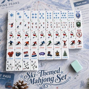 May include: A ski-themed mahjong set featuring white tiles with blue snowflake patterns, skiers, red gondolas, and winter icons. The tiles include labels like SOAP, GREEN, RED, JOKER, and FLOWER, alongside directional markers E, S, W, and N.