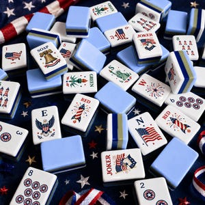 Puede incluir: Un conjunto de fichas de Mahjong azules y blancas con dise&ntilde;os patri&oacute;ticos estadounidenses, incluyendo la bandera americana, fuegos artificiales y la Estatua de la Libertad. Algunas fichas tienen las palabras "Joker", "Red" y "Green".