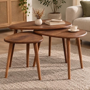 May include: A set of three nesting coffee tables made of dark brown wood with smooth, rounded triangular tops and tapered legs. The tables are arranged in a tiered formation, with the smallest table positioned in front of the two larger ones.