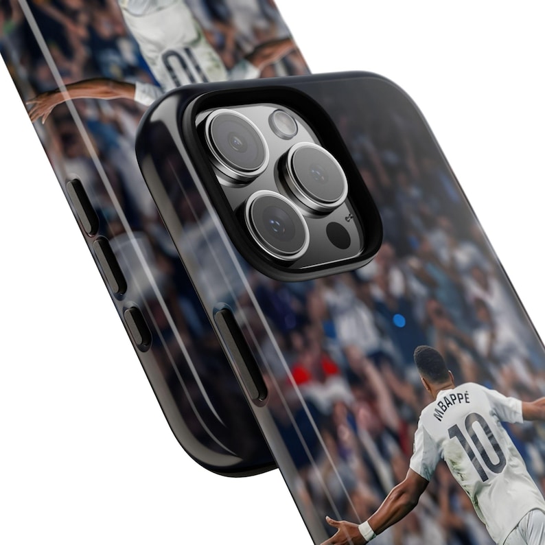 Pode incluir: Uma capa de smartphone preta com um gr&aacute;fico impresso de um jogador de futebol vestindo uma camisa branca com o nome MBAPPE e o n&uacute;mero 10 nas costas. A capa tem uma moldura preta, recortes precisos para as lentes e bot&otilde;es laterais.