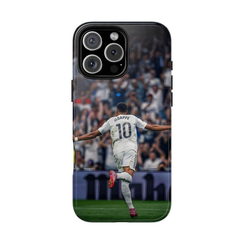 Pode incluir: Uma capa de smartphone preta com um gr&aacute;fico impresso de um jogador de futebol vestindo uma camisa branca com o nome MBAPPE e o n&uacute;mero 10 nas costas. O jogador &eacute; mostrado de costas, correndo em um campo verde com uma multid&atilde;o desfocada.