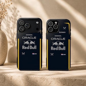 Peut inclure: Deux coques de smartphone bleu foncé arborant le logo Oracle Red Bull Racing, la marque Honda et des bandes verticales jaunes. Les motifs incluent le logo Castore, un petit drapeau néerlandais, le texte MAX et le logo Gate.io sur la coque droite.