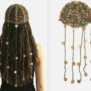 May include: A brown crocheted headpiece featuring a net-like structure adorned with small, multicolored sequins. The accessory includes several long, dangling strands decorated with circular gold-toned metal discs that hang down from the main cap.