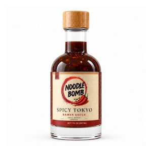 Könnte beinhalten: Eine klare Glasflasche "Noodle Bomb Spicy Tokyo Ramen Sauce" mit einem Holzdeckel. Das Etikett zeigt einen roten Kreis mit dem Markennamen und einer Chili-Pfeffer-Illustration. Die Flasche enthält eine dunkelrote Sauce und hat 207 ml.