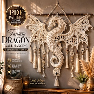 Könnte beinhalten: Ein cremefarbener Makramee-Wandbehang mit einem detaillierten Drachenmotiv aus komplexen Knoten, der an einer Holzstange hängt. Das Stück enthält hängende Quasten, metallische Mond- und Sonnenanhänger sowie klare, kristallartige Elemente.