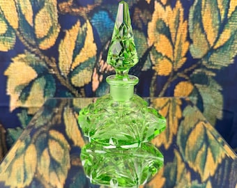 Frasco de perfume vintage em vidro de urânio verde com tampa facetada em estilo Art Déco que brilha sob luz UV.