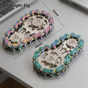 Könnte beinhalten: Zwei schillernde Metall-Fidget-Spinner mit einem Fahrradkettendesign um zwei silberfarbene Zahnräder. Jeder Spinner misst 60 mm in der Länge und 35 mm in der Breite bei einem Nettogewicht von 45 g. Die Kettenglieder zeigen einen Regenbogenverlauf.