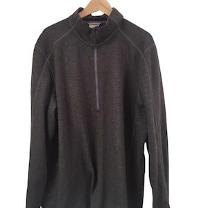 May include: A charcoal gray long-sleeve pullover featuring a quarter-zip neckline with a stand-up collar. The garment is constructed from a textured fleece material and includes visible seam detailing along the shoulders and sleeves.