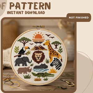 May include: A cross-stitch pattern in a wooden hoop featuring a safari theme with a lion, giraffe, elephant, zebra, toucan, rhino, hippo, and crocodile. The text reads PDF PATTERN INSTANT DOWNLOAD and NOT FINISHED. The design includes a sun and trees.