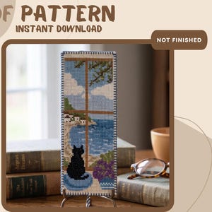 May include: A cross-stitch bookmark pattern featuring a black cat sitting on a blue cushion, looking out a window at a blue sea, white buildings, and a green tree. The text PDF PATTERN INSTANT DOWNLOAD and NOT FINISHED are visible.