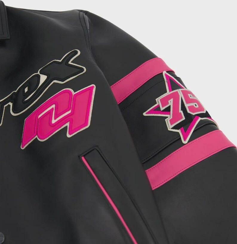 May include: A black leather jacket featuring bright pink accents, including horizontal stripes on the sleeve and a large pink number 75 inside a star-shaped patch. The jacket displays a large pink number 14 and partial black text on the chest.