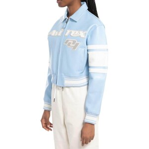 May include: A light blue varsity-style jacket featuring a white collar, white striped ribbed cuffs and hem, and white sleeve panels. The chest displays the embroidered text "Avirex" and the letters "NY" in a layered white and grey font design.