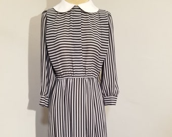 May include: A black and white striped dress with a white Peter Pan collar. The dress has long sleeves and a fitted waist.