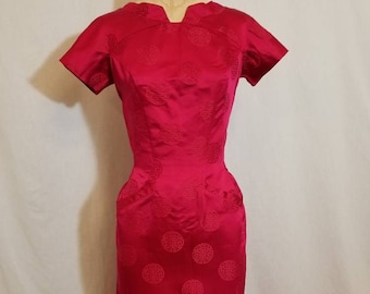 Puede incluir: Un vestido rojo vintage de manga corta y silueta ajustada. El vestido está cubierto de un patrón repetitivo de diseños circulares.