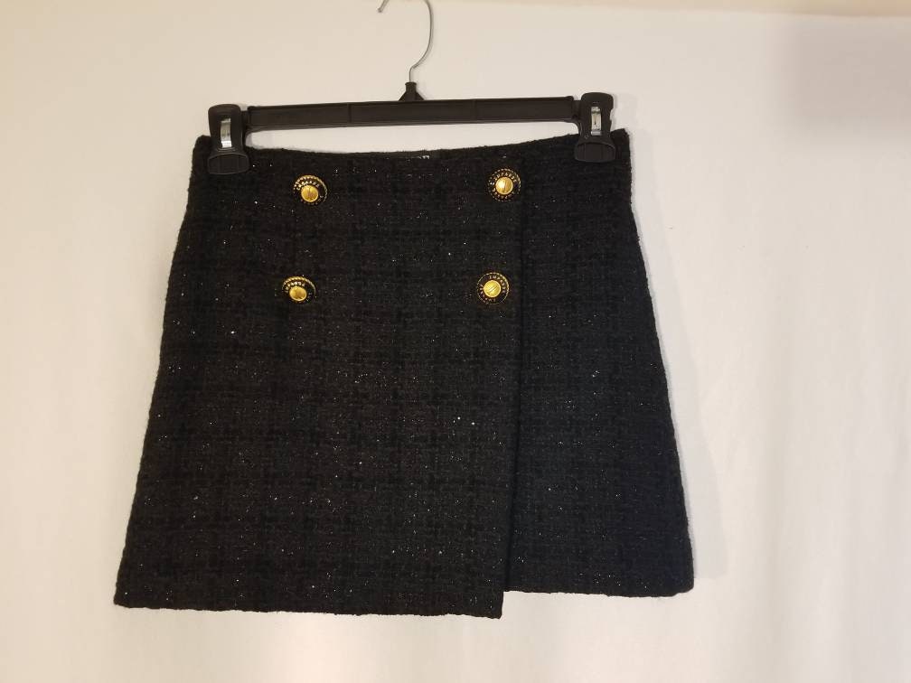 FALDA DE BOUCLE NEGRA Falda cruzada con botones dorados de tweed