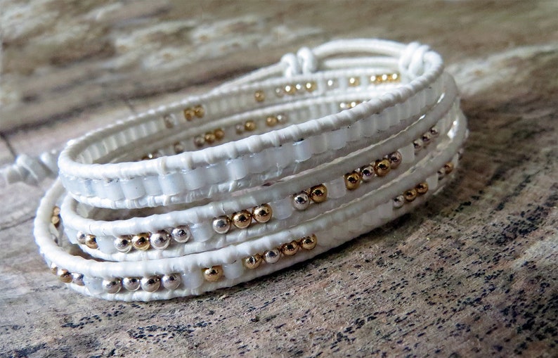 May include: White leather wrap bracelet with gold and silver beads.