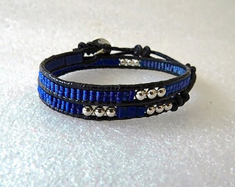 May include: A double wrap leather bracelet with blue and silver beads. The bracelet is tied with a knot on each end.
