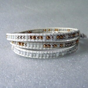May include: White leather wrap bracelet with silver and gold beads.