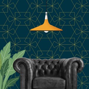 May include: A dark teal wallpaper with a repeating thin gold geometric line pattern, featuring a black tufted leather armchair, a potted green plant with broad leaves, and a hanging pendant light with a textured orange conical shade.