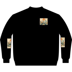 Peut inclure: Un sweat-shirt noir à manches longues avec un petit motif rectangulaire sur la poitrine et des motifs rectangulaires assortis sur chaque manche. Les imprimés représentent un paysage urbain stylisé avec la Statue de la Liberté et la Tour Eiffel.